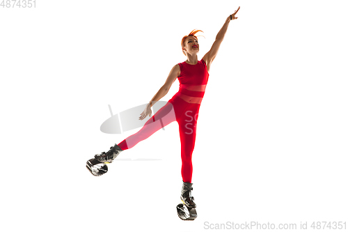 Image of Beautiful redhead woman in a red sportswear jumping in a kangoo jumps shoes isolated on white studio background.