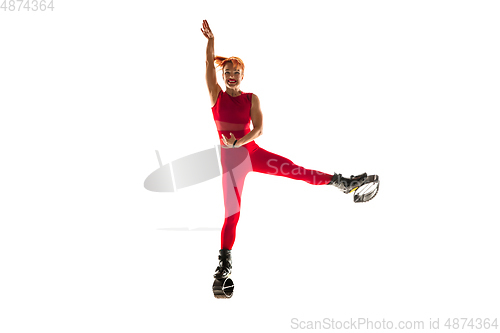 Image of Beautiful redhead woman in a red sportswear jumping in a kangoo jumps shoes isolated on white studio background.