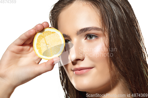 Image of Citrus. Close up of beautiful female face with lemon slices over white background. Cosmetics and makeup, natural and eco treatment, skin care.