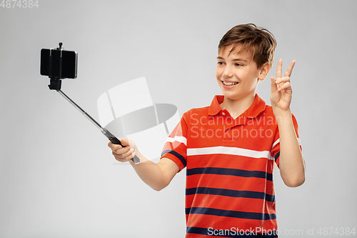 Image of boy taking picture with smartphone on selfie stick