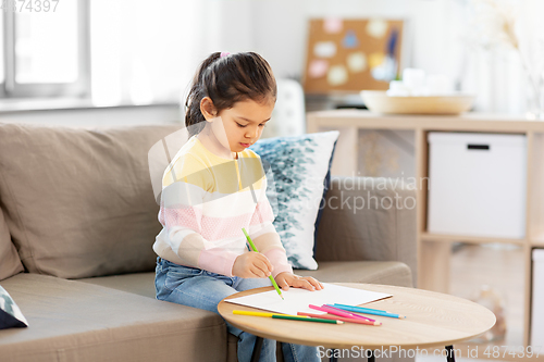 Image of little girl drawing with coloring pencils at home