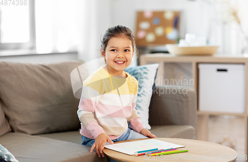 Image of little girl drawing with coloring pencils at home