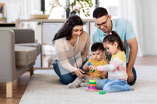 Image of happy family playing with pyramid toy at home