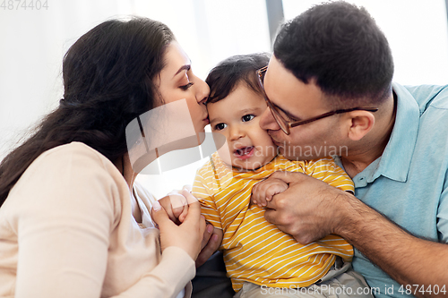 Image of happy mother and father kissing baby son at home