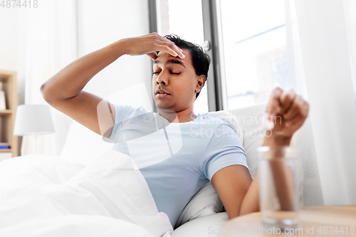 Image of sick man in bed with medicine and glass of water