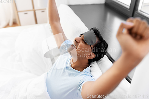 Image of happy smiling indian man lying in bed at home