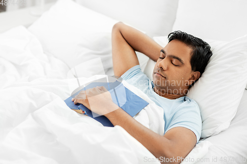 Image of indian man with book sleeping in bed at home