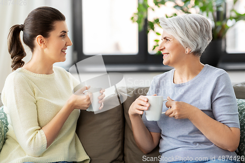 Image of senior mother and adult daughter drinking coffee