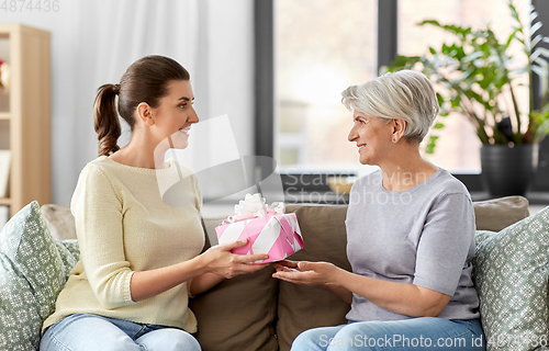 Image of adult daughter giving present to her senior mother