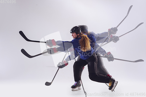 Image of Young female hockey player with the stick on ice court and white background, action and motion concept