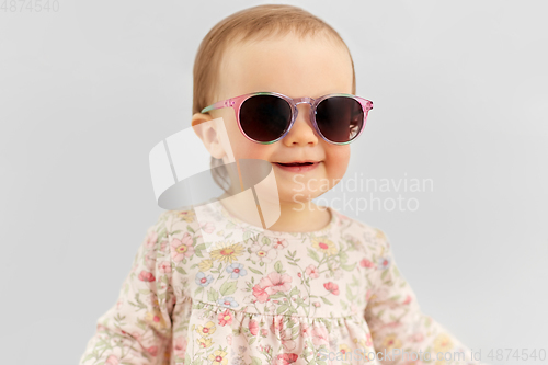 Image of happy little baby girl in sunglasses over grey