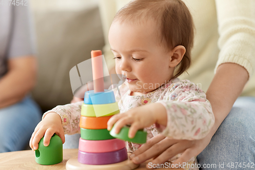 Image of lovely baby girl playing with toy pyramid at home