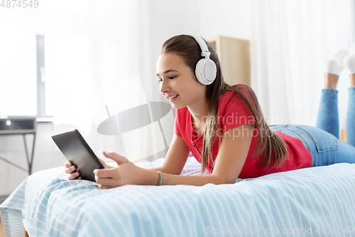 Image of girl in headphones listening to music on tablet pc