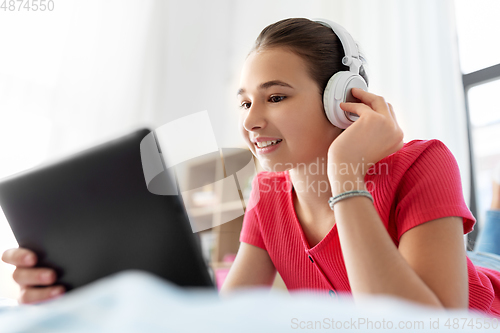 Image of girl in headphones listening to music on tablet pc