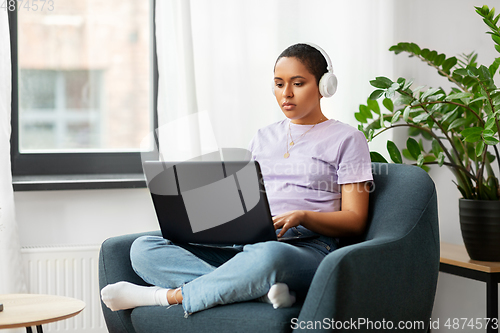 Image of woman with laptop listening to music at home