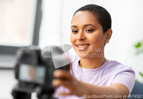 Image of female video blogger adjusting camera at home