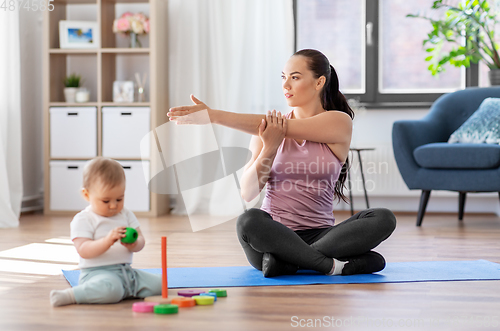 Image of happy mother with little baby exercising at home