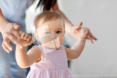 Image of baby girl learning to walk with mother's help