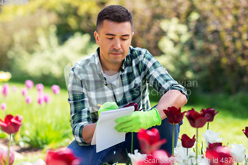 Image of man with notebook and flowers at summer garden