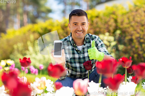 Image of man with phone showing thumbs up at flowers garden