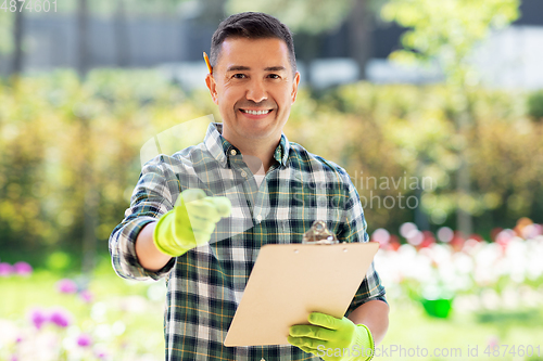 Image of happy smiling man with clipboard at summer garden