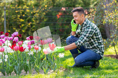 Image of man with flowers calling on smartphone at garden