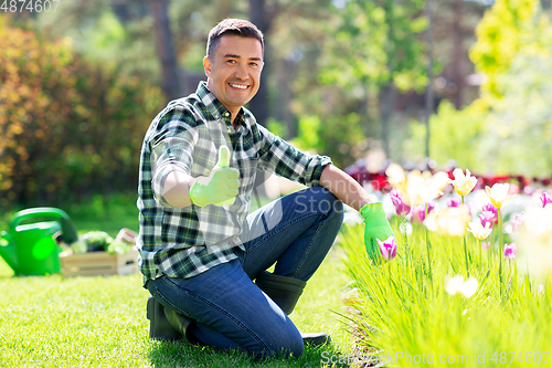 Image of happy man with flowers showing thumbs up at garden