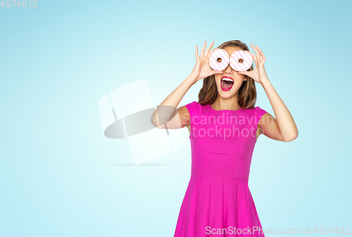 Image of happy woman or teen girl having fun with donuts