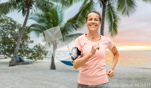 Image of woman with earphones add armband jogging at park