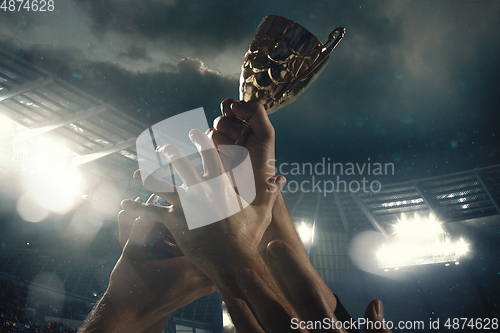 Image of Award of victory, male hands tightening the cup of winners against cloudy dark sky