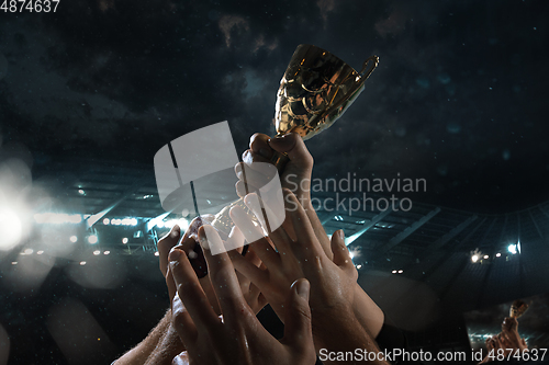 Image of Award of victory, male hands tightening the cup of winners against cloudy dark sky