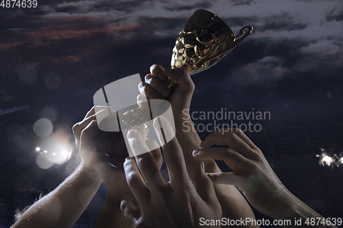 Image of Award of victory, male hands tightening the cup of winners against cloudy dark sky