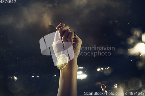 Image of Award of victory, male hands tightening the medal of winners against cloudy dark sky