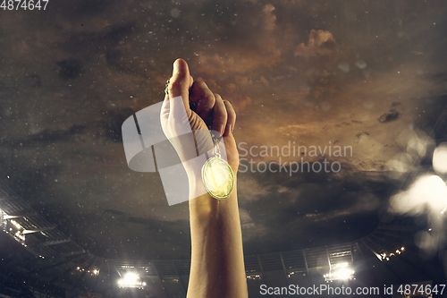 Image of Award of victory, male hands tightening the medal of winners against cloudy dark sky