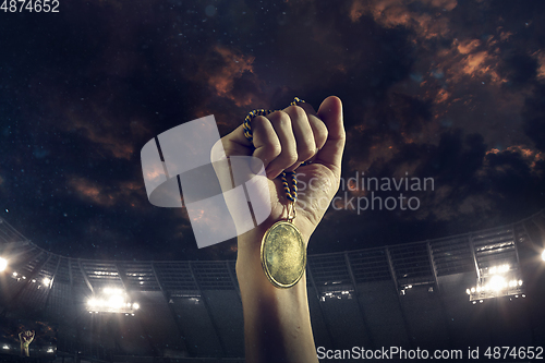 Image of Award of victory, male hands tightening the medal of winners against cloudy dark sky