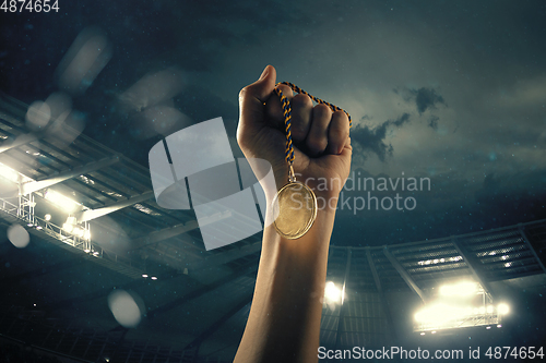 Image of Award of victory, male hands tightening the medal of winners against cloudy dark sky