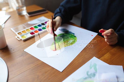 Image of Girl drawing with paints and pencils at home, watching teacher\'s tutorial on laptop. Digitalization, remote education