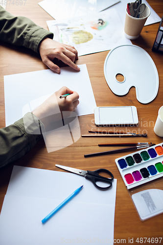 Image of Close up of man drawing with paints and pencils at home. Remote education, creative occupation, art therapy