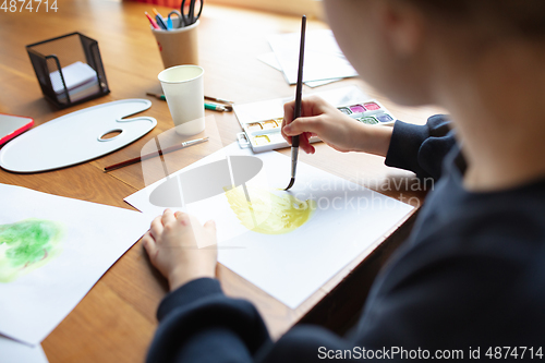 Image of Girl drawing with paints and pencils at home, watching teacher\'s tutorial on laptop. Digitalization, remote education