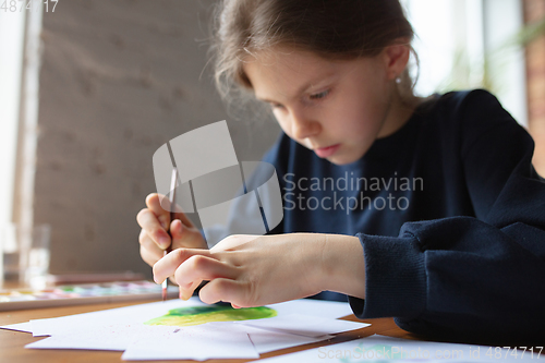 Image of Girl drawing with paints and pencils at home, watching teacher\'s tutorial on laptop. Digitalization, remote education