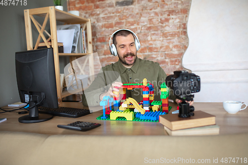 Image of Man giving online lesson with constructor at home. Recording teacher\'s tutorial on camera for kids. Digitalization, remote education