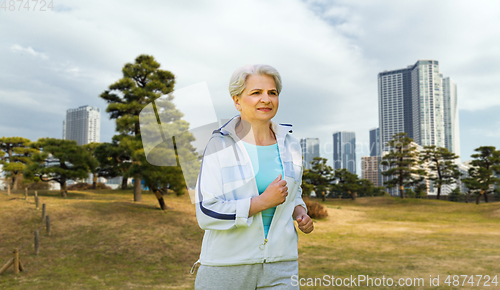 Image of senior woman running along summer park