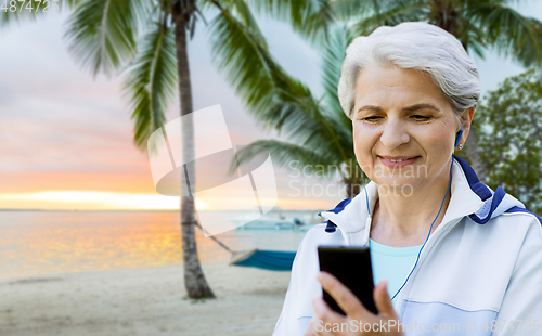 Image of sporty senior woman with earphones and smartphone