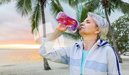 Image of senior woman drinks water after exercising in park