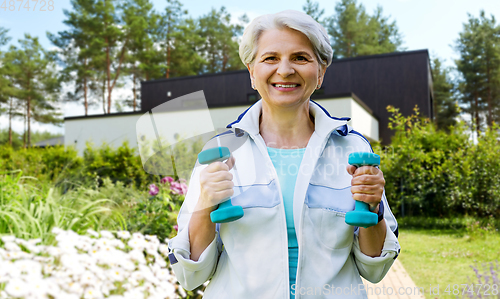 Image of senior woman with dumbbells exercising at park