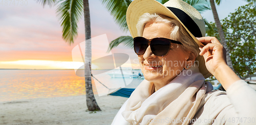Image of happy senior woman in sunglasses and hat on beach