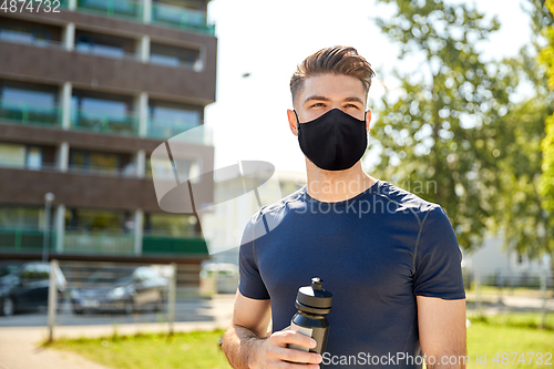 Image of young sporty man with bottle outdoors