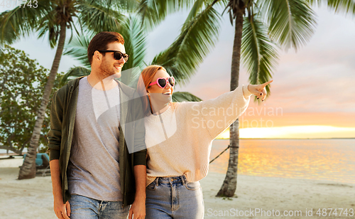 Image of happy couple walking along summer beach