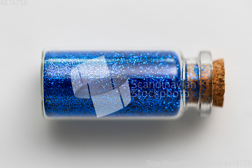 Image of blue glitters in bottle over white background