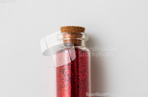 Image of red glitters in bottle over white background